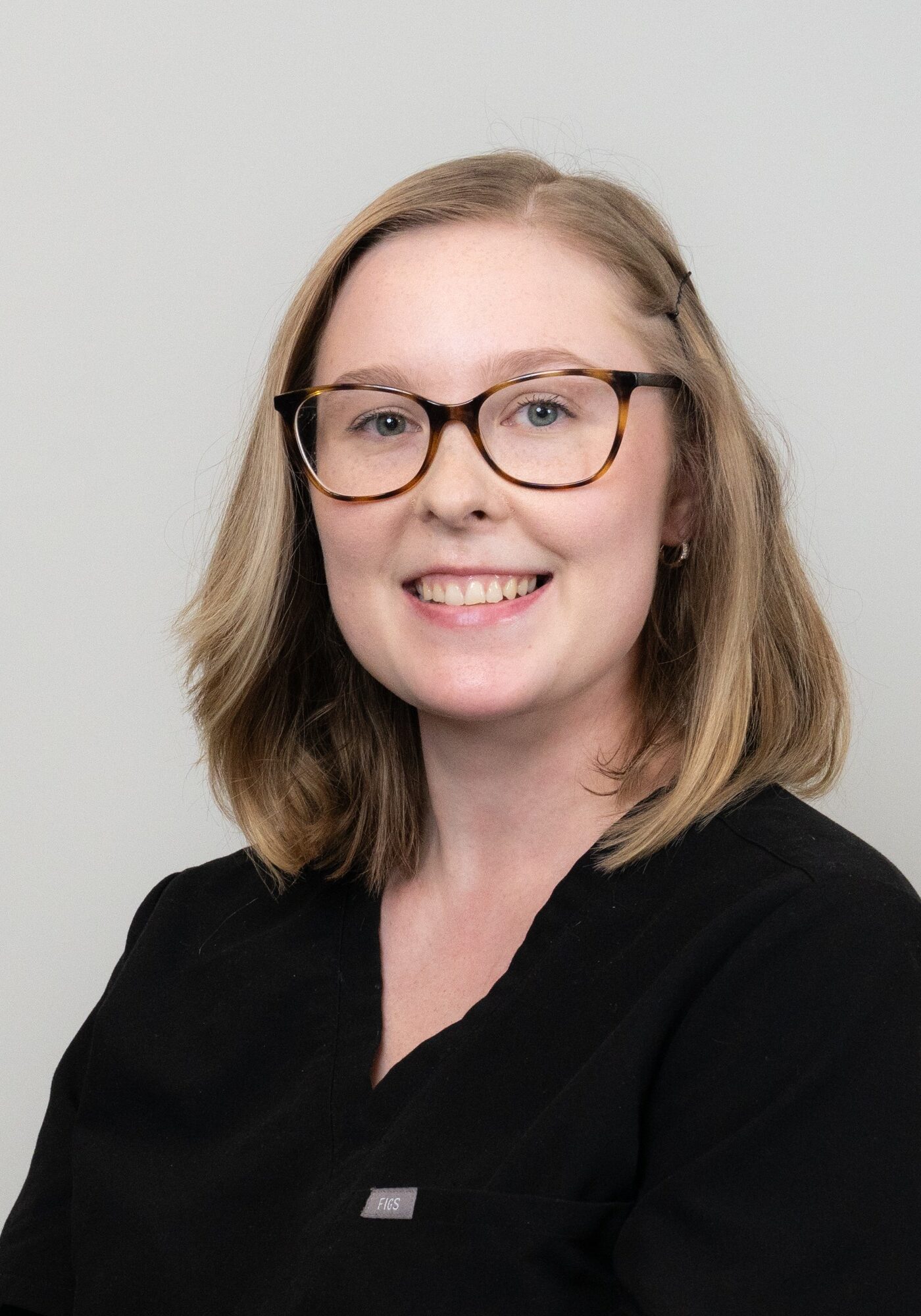 Aaliyah, smiling orthodontic tech in black scrubs, showcasing friendly demeanor for Hoagburg Orthodontics team.