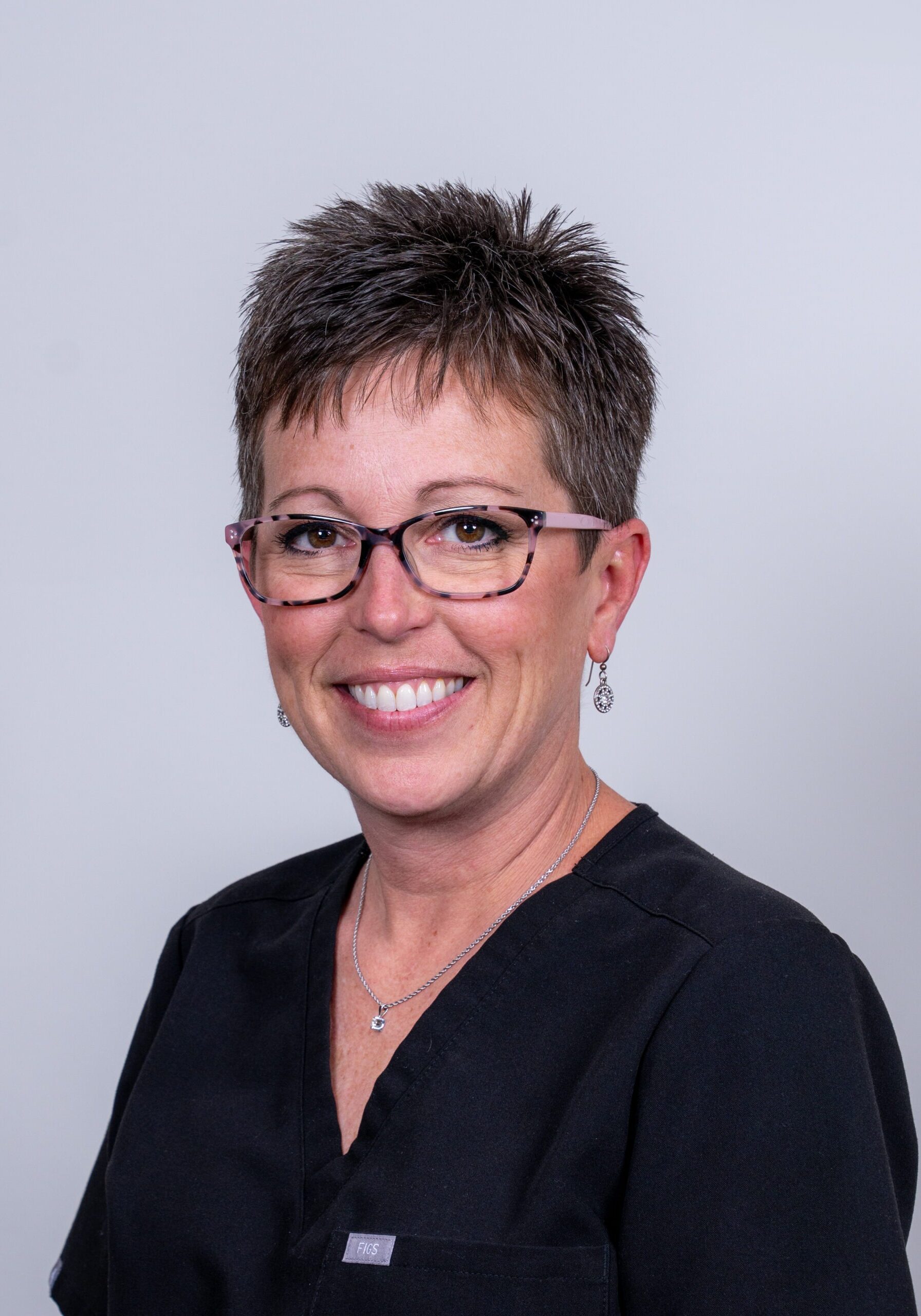 Scheduling Coordinator and Treatment Coordinator at Hoagburg Orthodontics, smiling in a black uniform with short hair and glasses.