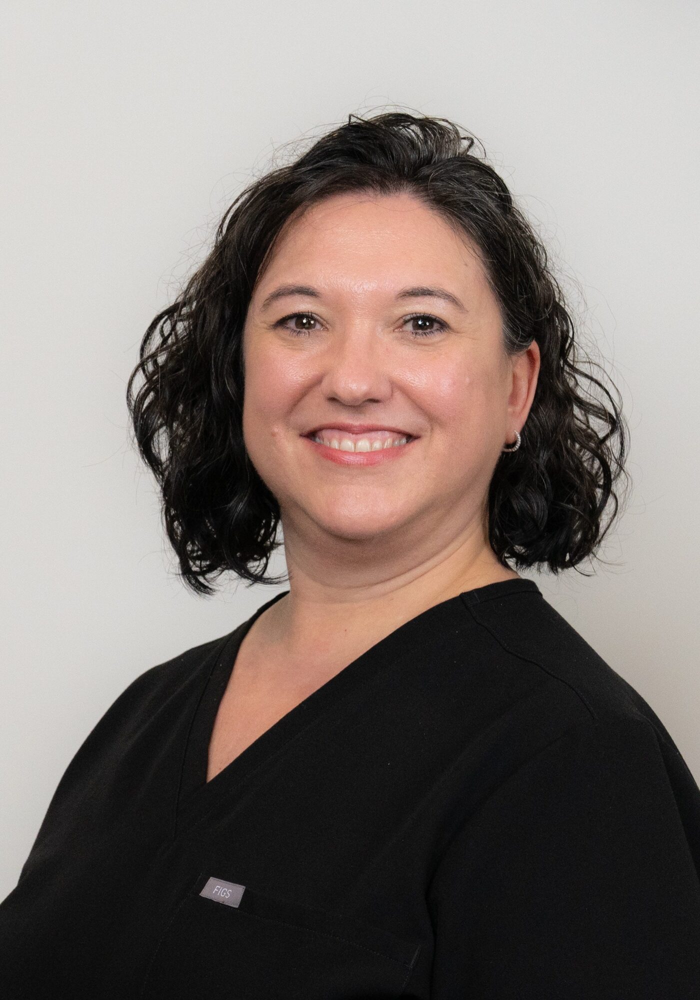 Heather, scheduling coordinator at Hoagburg Orthodontics, smiling in a black scrub top against a neutral background.