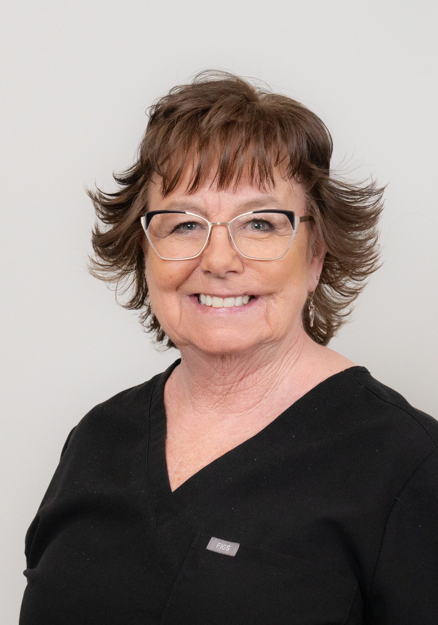 Sarah, Treatment Coordinator at Hoagburg Orthodontics, smiling in black scrubs, showcasing expertise and friendly demeanor.